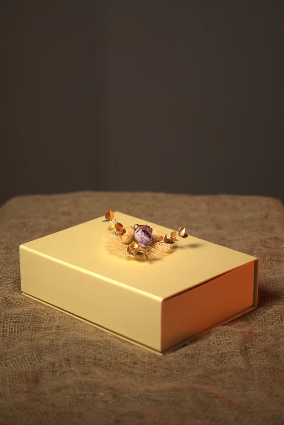 A closed cream gift box finished with a floral brooch