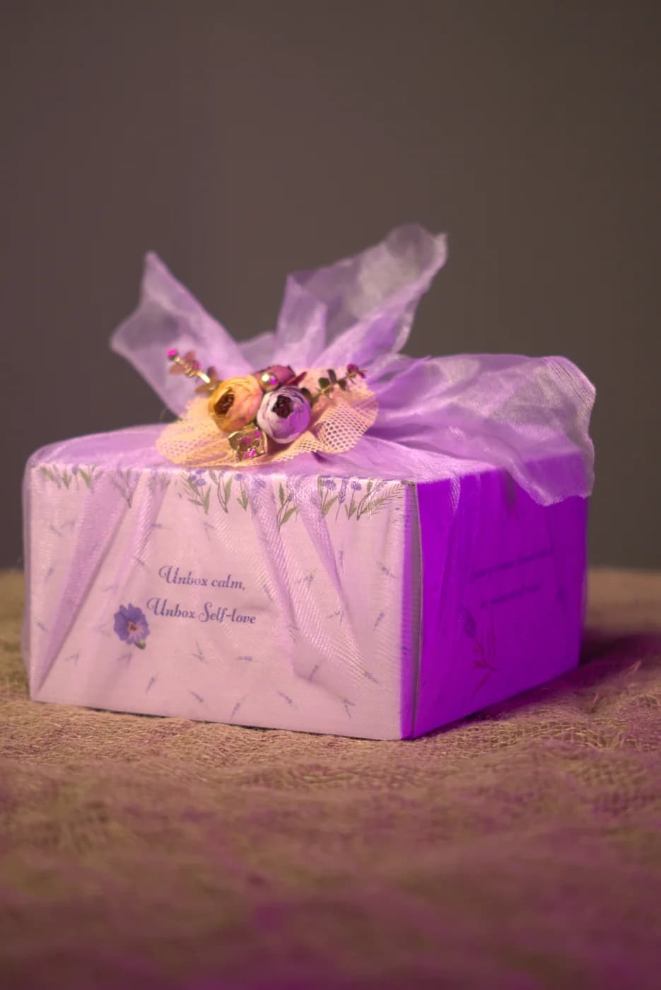 A gift box wrapped in sheer lavender tulle with a floral brooch