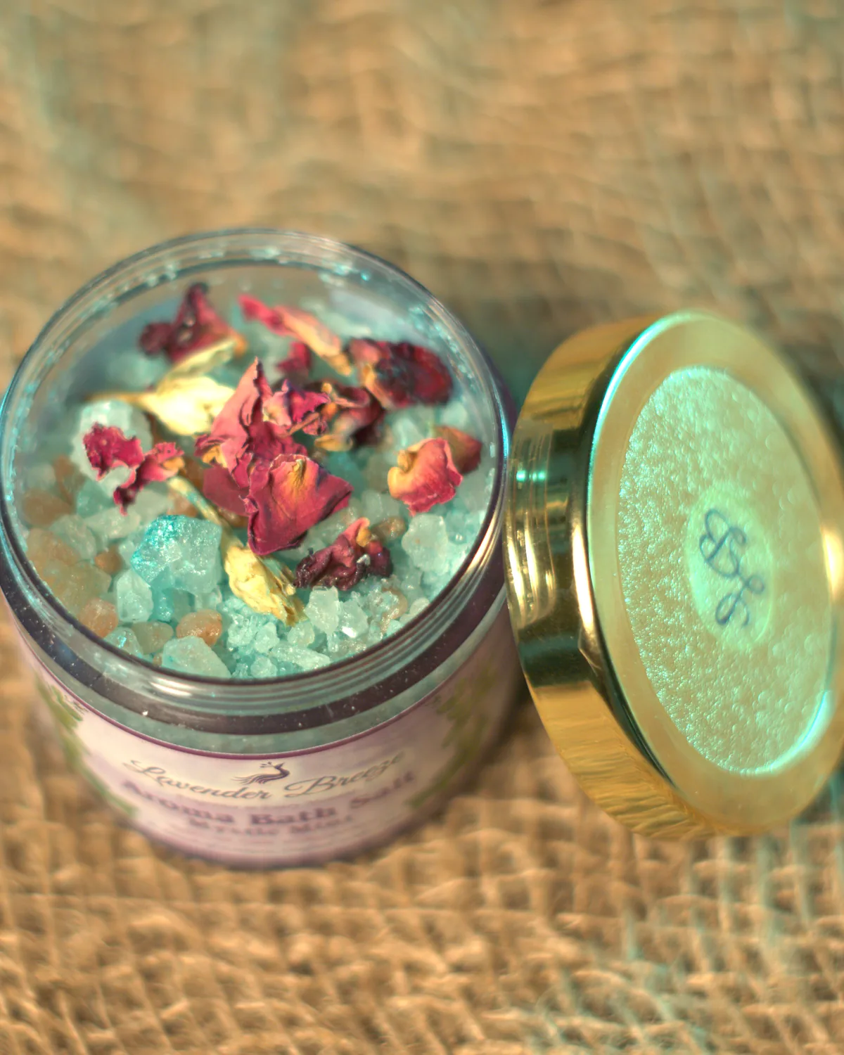 An open jar of Mystic Mint bath salt with rose petals, seen from above