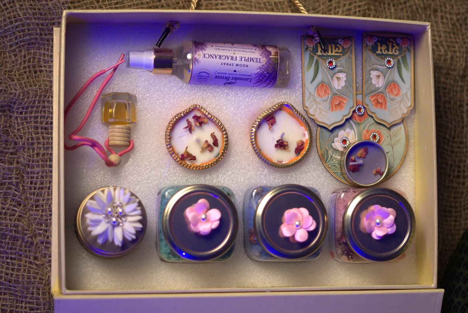 A hamper seen from above: room spray, car perfume pod, diyas, potpourri and bath salt jars
