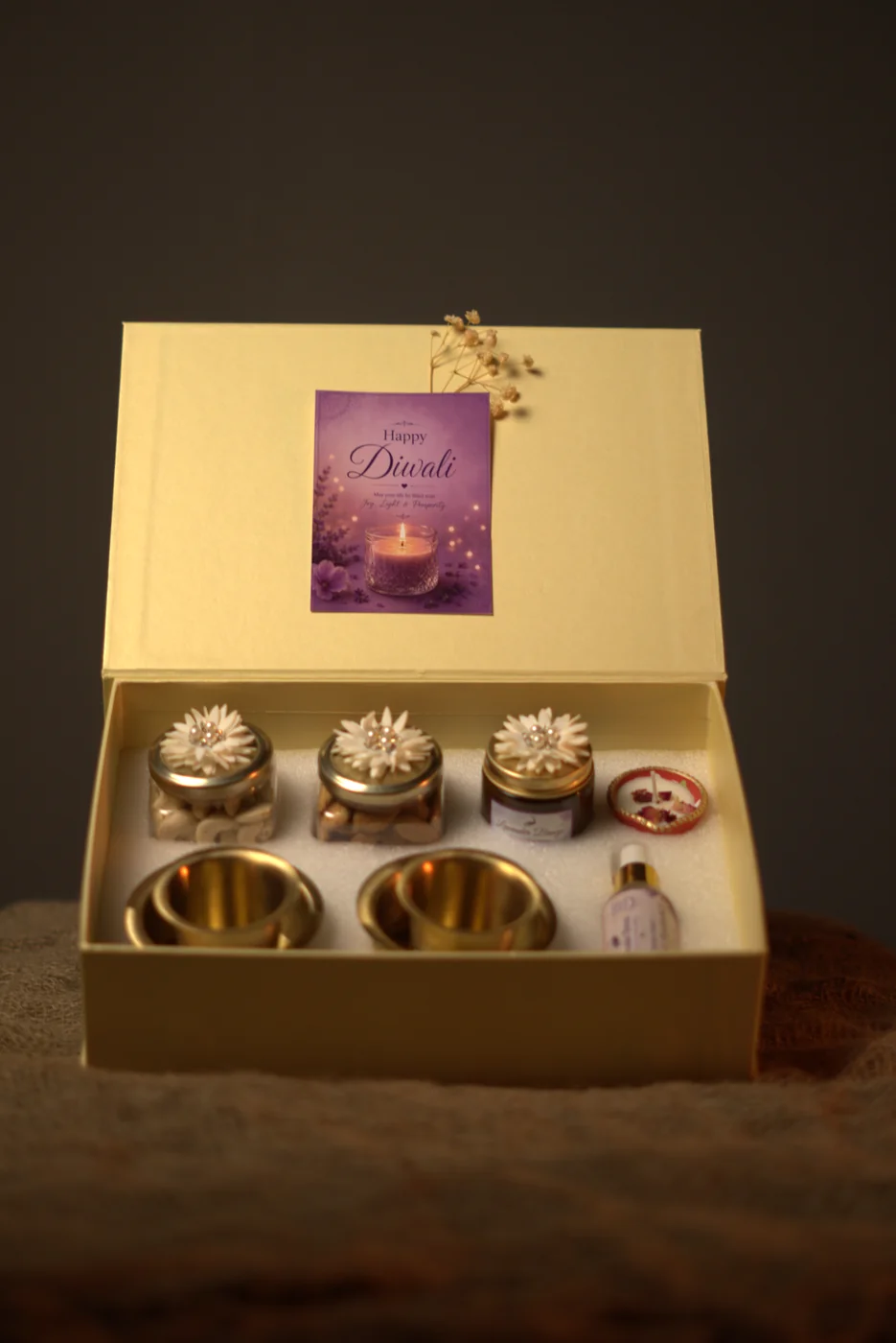 A gold Lavender Breeze hamper with a Diwali card, nut jars and brass tumblers