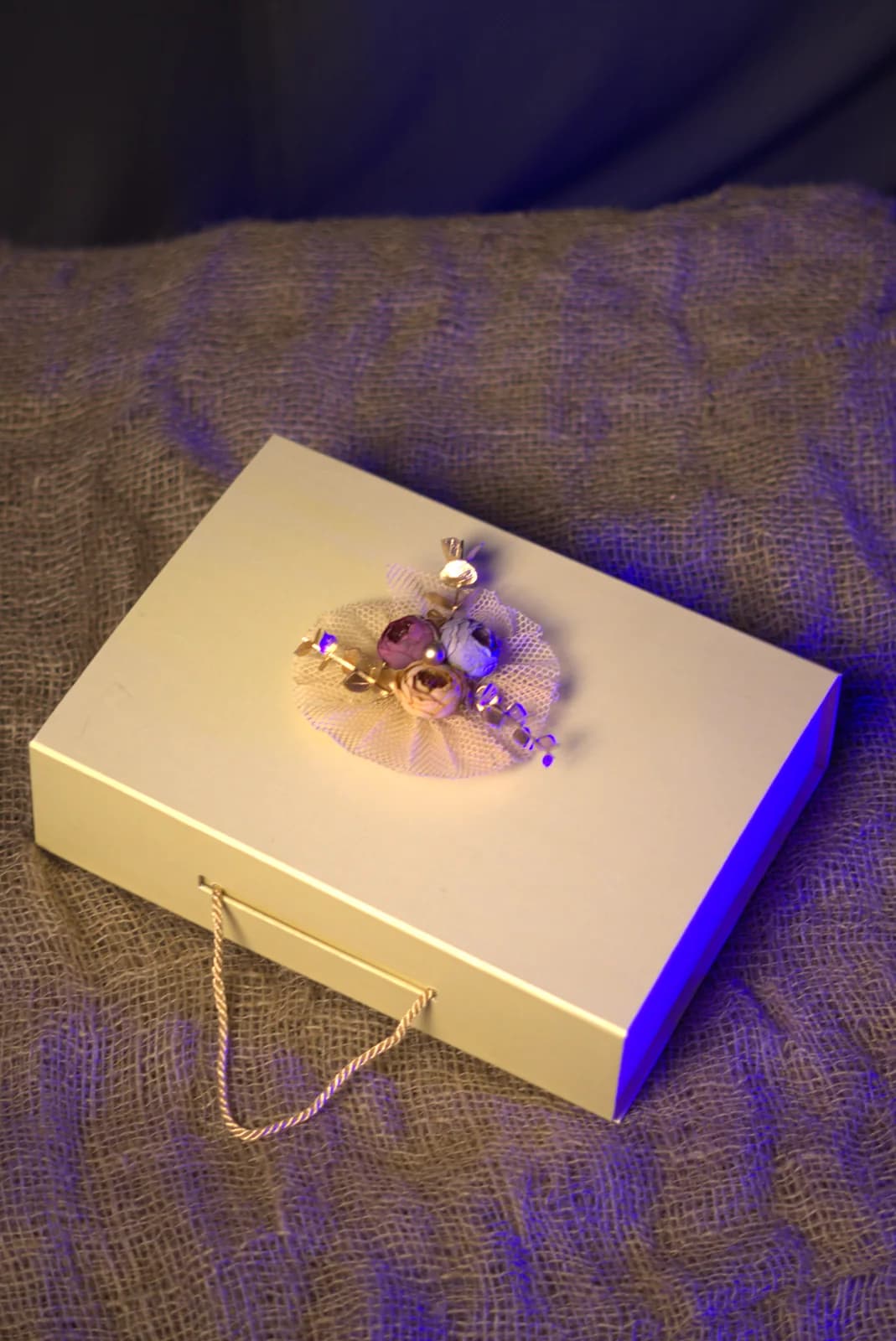 A finished cream hamper box with a floral brooch and rope handles