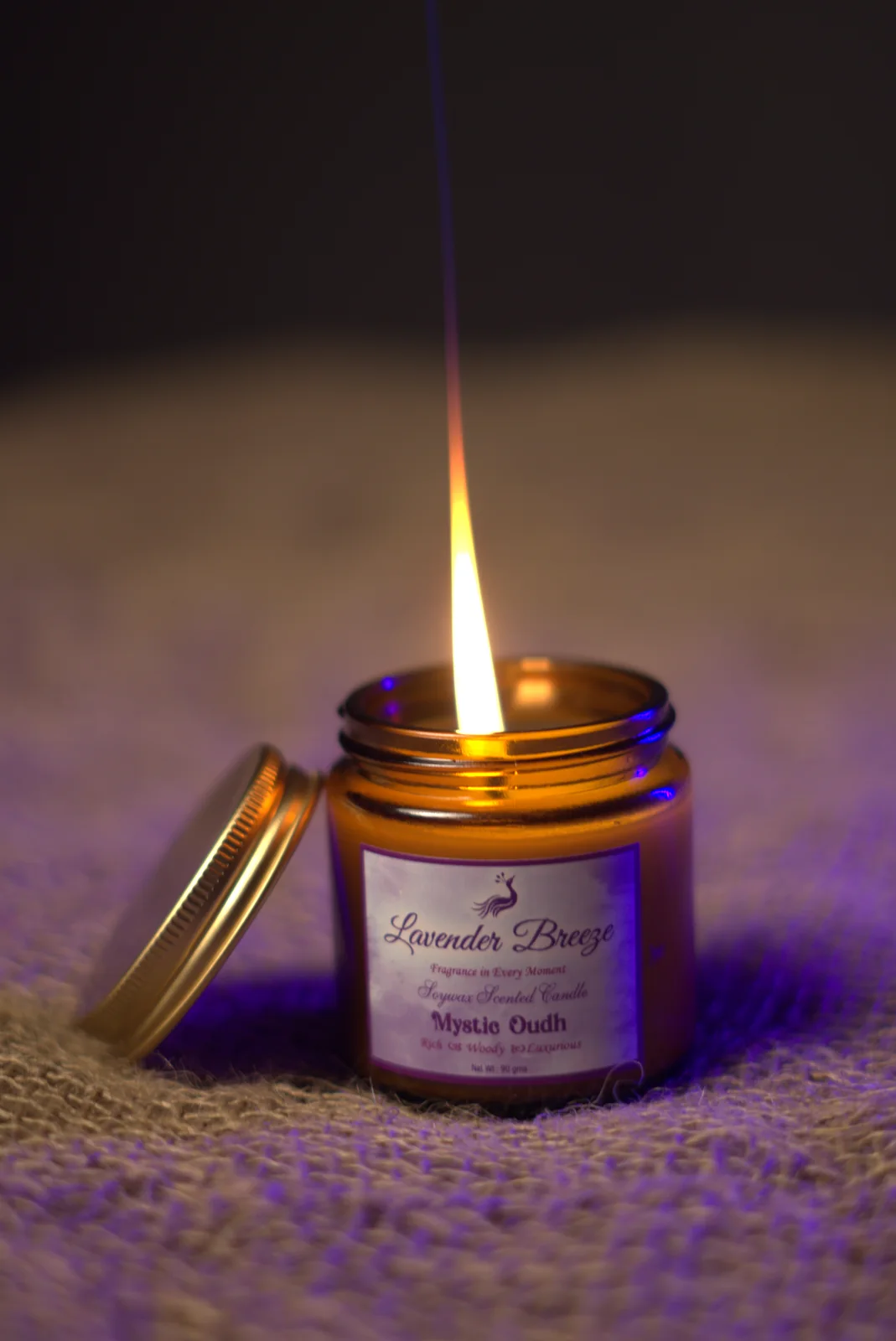A lit Mystic Oud soy wax candle in an amber glass jar